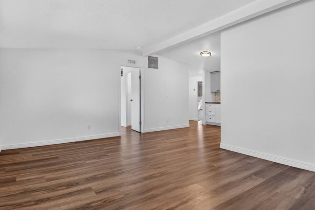A hardwood floor shows the contrast between the original finish and the freshly sanded wood surface during the refinishing process.
